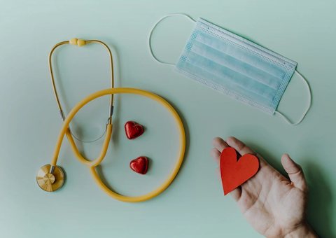 A stethoscope beside red hearts on a soft green background