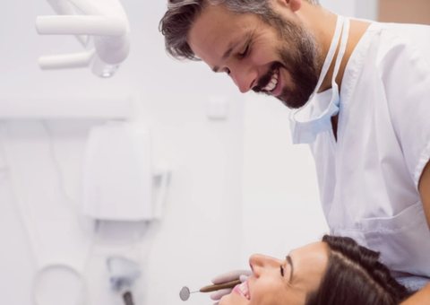 A smiling dentist examining a relaxed patient's teeth